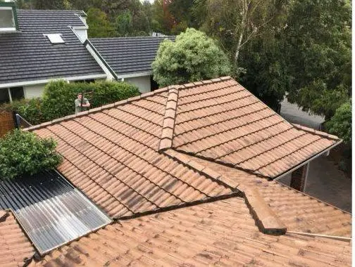 Weathered terracotta hip roof with worn ridge capping before restoration